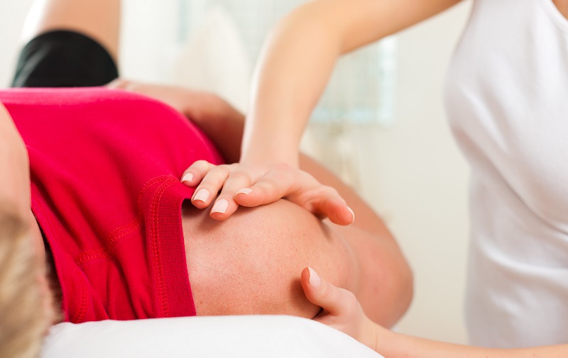 Man lying on back receiving massage on right shoulder